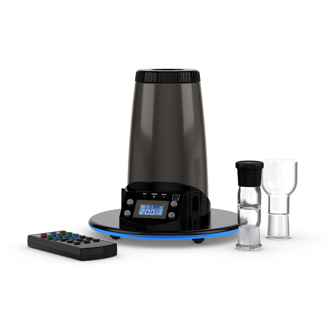 A comprehensive studio product layout showing the Arizer Extreme Q Desktop Vaporizer standing alongside all its included box accessories. The midnight-chrome device is surrounded by the wireless remote control, two glass Cyclone Bowls, a glass aromatherapy dish, a 3-foot silicone whip, glass balloon mouthpieces, pre-assembled balloon bags, replacement screens, and the power supply unit on a clean background.