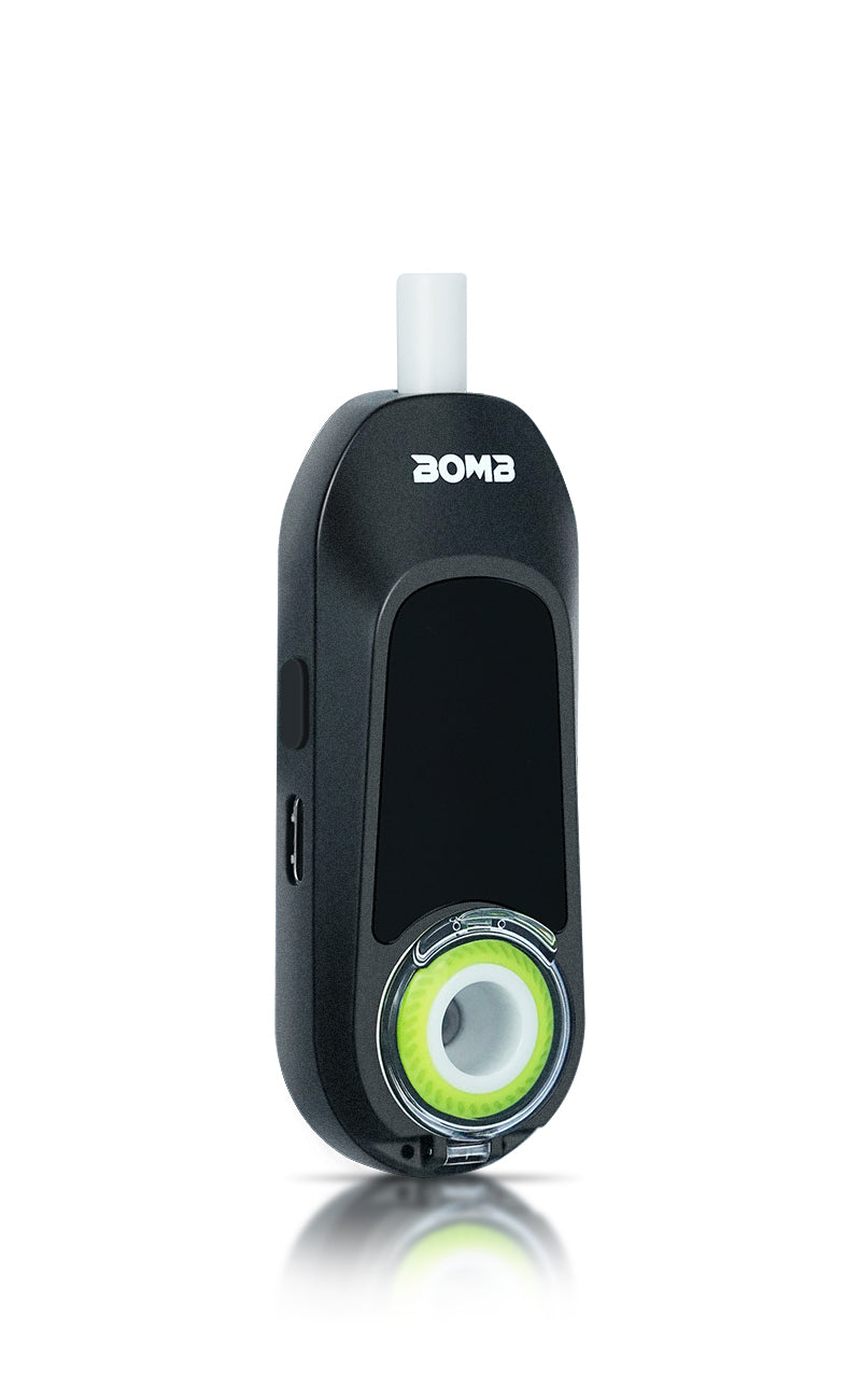 An angled side-front view of the Bomb × VapX Magic Bean in Onyx Black. The image showcases the built-in ceramic concentrate bowl, the digital display screen, and the integrated USB-C charging port with the universal control button positioned just above it.
