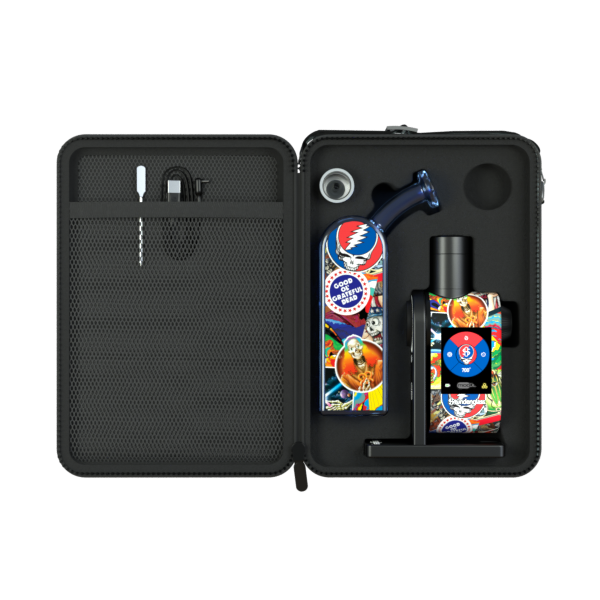 A high-angle studio shot looking inside the open Grateful Dead x Stündenglass Legacy Patchwork Deluxe Travel Case. The image showcases the premium, custom-molded foam interior slots, revealing how the custom-artwork Dok handle, digital Modül power base, borosilicate glass globe, heating tanks, and accessories are safely organized and securely isolated for high-impact travel protection.