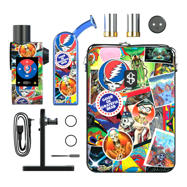 A comprehensive studio layout shot displaying the entire Grateful Dead x Stündenglass Modül + Dok Legacy Patchwork Deluxe Travel Set. The zippered hardshell carrying case sits alongside the disassembled components, including the handheld Dok base station, the digital Modül battery unit, both dry material and quartz concentrate heating tanks, the magnetic connection rings, a metal loading tool, and the fast-charging cable spread neatly on a clean background.