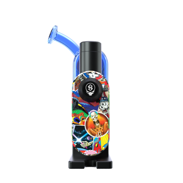 A detailed studio product profile shot showcasing the Grateful Dead x Stündenglass Modül + Dok Legacy Patchwork edition from the side. The view focuses on the premium textures of the handheld glass docking station base, displaying a unique section of the vibrant, officially licensed Grateful Dead patchwork graphics and the secure placement of the digital Modül battery unit.