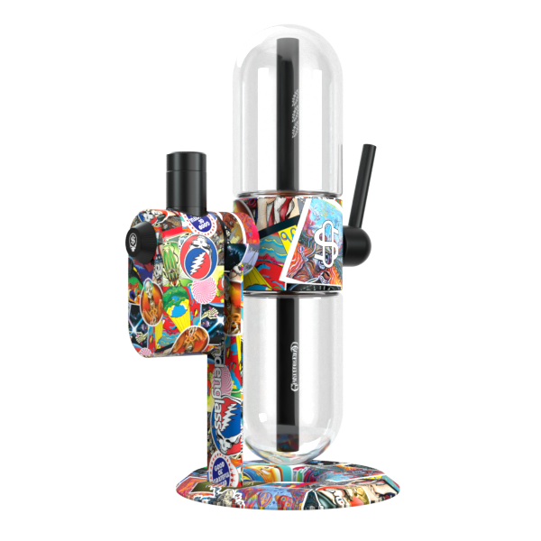 A clean, rear-angle studio product shot displaying the Grateful Dead x Stündenglass Modül smart power base mounted onto the full-sized Grateful Dead Gravity Infuser. This view focuses on the rear mechanical connections and structural design of the heavy-duty gravity hookah, showcasing how the continuous patchwork band graphics fully wrap around the back assembly to complete the high-end collector look.