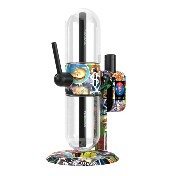 A crisp, front-angle studio product shot showcasing the Grateful Dead x Stündenglass Modül smart power base docked onto the full-sized Grateful Dead Gravity Infuser from the opposite side. The perspective highlights the clean symmetry of the premium glass setup, focusing on the vibrant, multi-paneled licensed patchwork band imagery and the sleek profile of the clear rotating borosilicate glass globes.