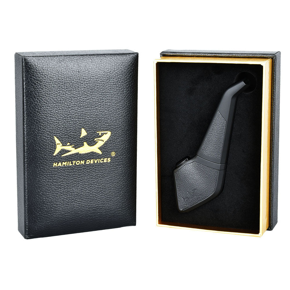 A side-by-side presentation of The Hamilton Devices PB1 Pipe Vape retail packaging. On the left stands the fully enclosed black box with elegant product branding; on the right, an open box reveals the precision-cut internal protective foam insert securely housing the pipe-shaped battery and its premium accessories.