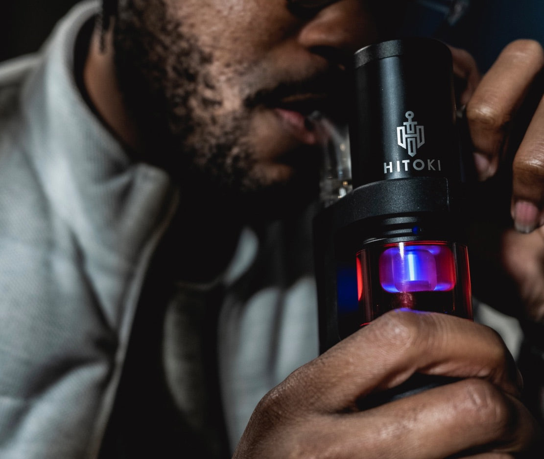 A second in-hand view of the Hitoki Saber Portable Kit, showcasing the thumb-activated power button and the comfortable, matte black textured grip. This shot highlights the device's portability and ease of