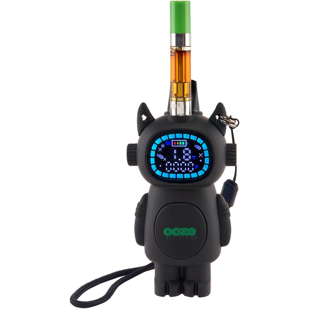 The Ooze Bot with a 510-thread cartridge screwed into the top port and a short black wrist lanyard installed through the side anchor point. The digital display is active, showing the variable voltage interface and highlighting the device’s ready-for-travel design.