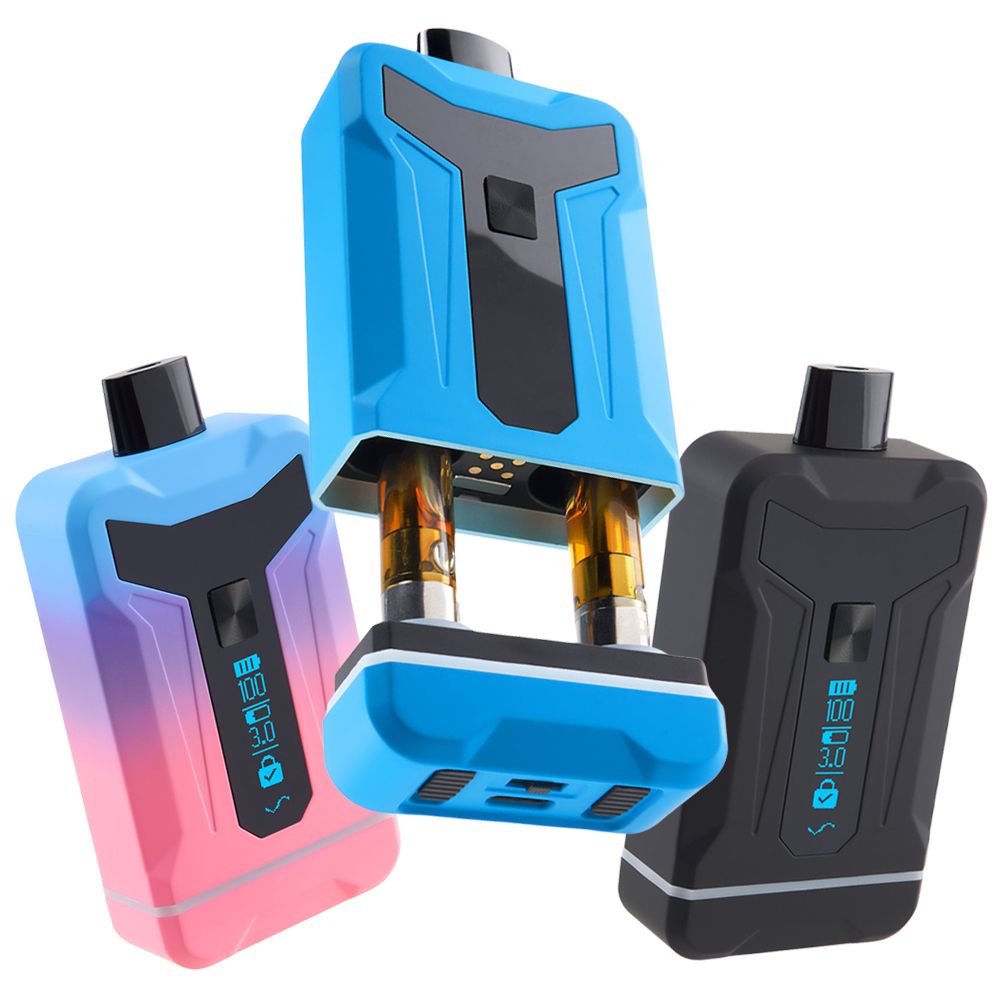 A crisp studio product lineup displaying three colorways of the Ooze Duet vape battery side-by-side. The lineup showcases the smooth, rounded rectangular devices in Twilight (a vibrant pink, purple, and blue gradient finish), solid Matte Black, and a clean Royal Blue. The Royal Blue model is shown with its protective upper magnetic cover slid halfway off, cleanly exposing two standard 510-threaded oil cartridges installed in the internal dual-firing bay.