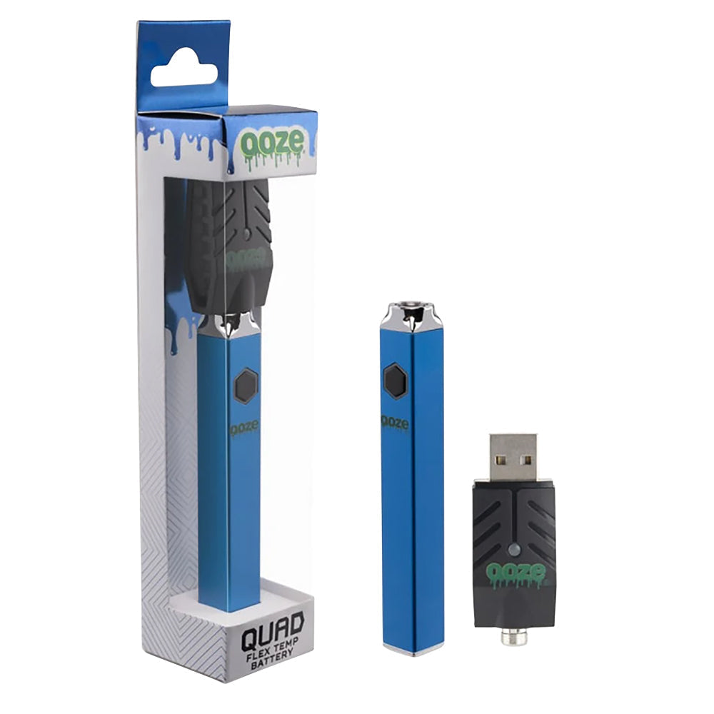 A clean studio shot highlighting the Ooze Quad Flex Temp square vape pen in Sapphire Blue. The rich, metallic dark blue battery is positioned upright next to its official clear-window retail packaging box, showcasing its unique flat-edged square anti-roll geometry alongside the included black screw-on USB charging accessory.