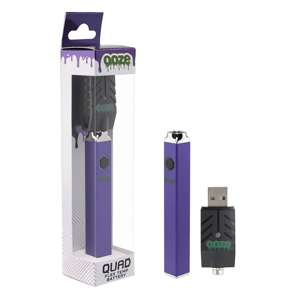 A crisp studio product shot showing the Ooze Quad Flex Temp square 510 battery in Ultra Purple. The vibrant, metallic violet-purple pen stands vertically next to its transparent plastic retail pegboard packaging, with the signature black screw-on 510-threaded USB smart charger resting in the foreground.