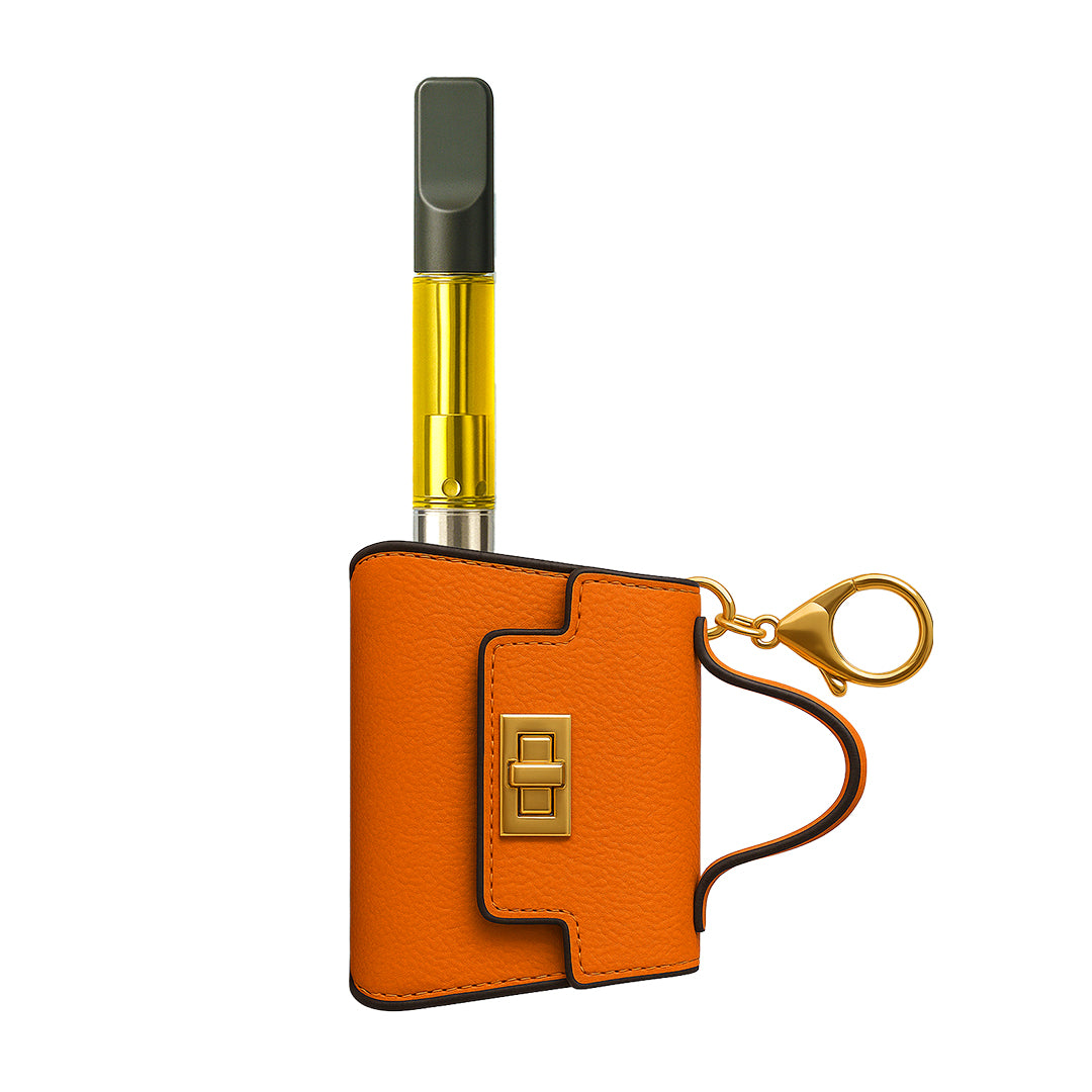 Bright orange pebble-grain leather Penjamin Pursejamin 510 battery, designed as a luxury handbag charm with a gold lobster claw keychain and internal cartridge chamber.
