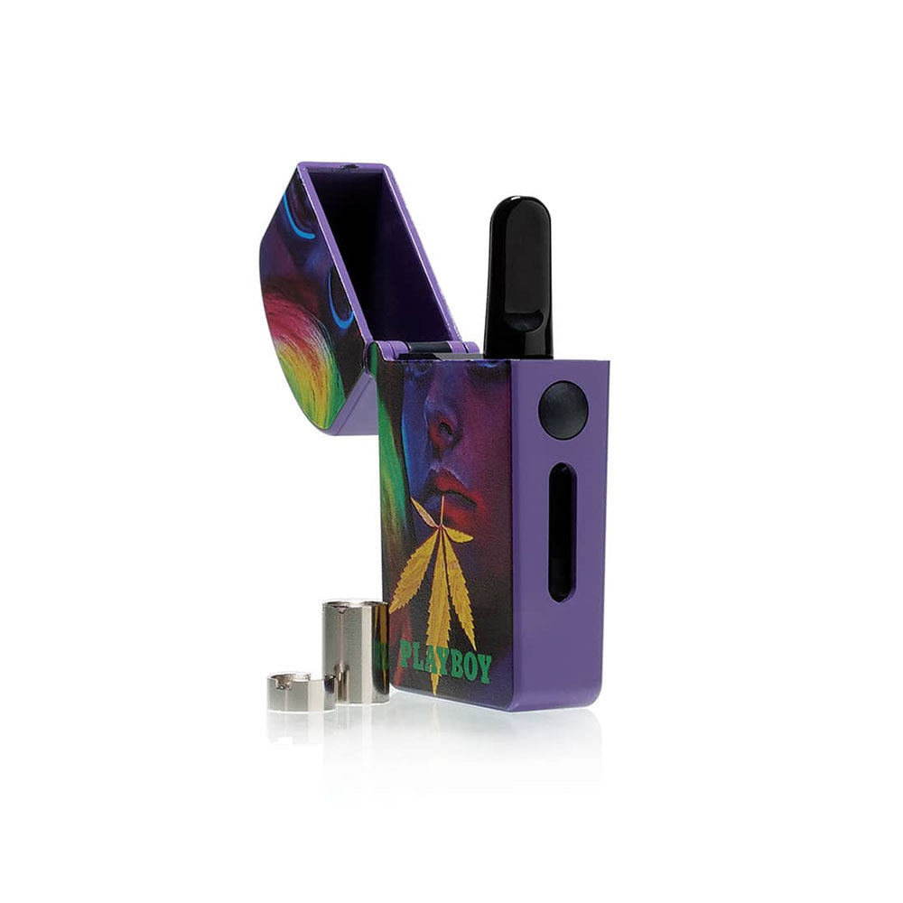 A detailed studio product shot of the Playboy x RYOT VERB 510 vape battery in the Playboy Leaf design with its top lid flipped wide open. The internal compartment displays a 510 oil cartridge magnetically installed, while the two gold-plated magnetic connector ring adapters rest cleanly on the display surface right next to the device base.