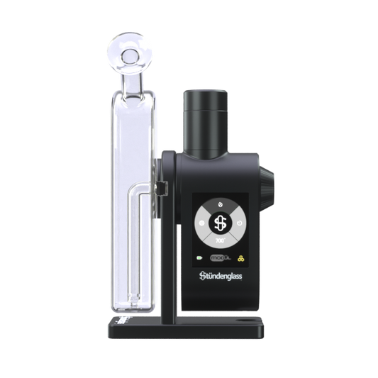 A premium studio product shot displaying the fully assembled Stündenglass Modül + Dok Deluxe Travel Set in Clear Glass standing upright on a clean gray background. Positioned directly next to the elegant, handheld anodized aluminum e-rig is its official hardshell fabric travel case, shown unzipped to highlight its custom-molded protective compartments and rugged drop-resistant build.