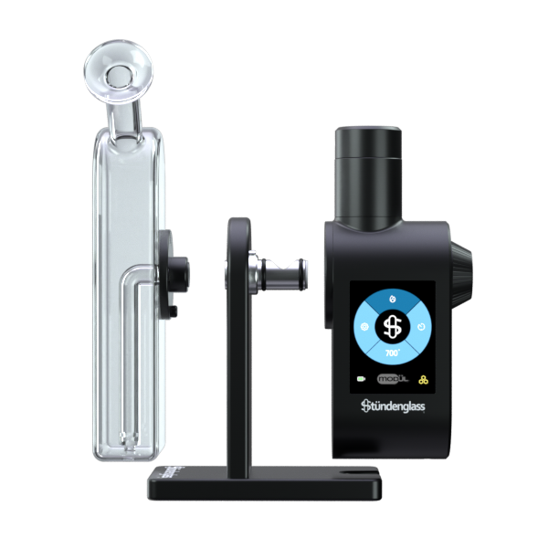 A detailed, front-facing studio demonstration shot highlighting the modular assembly of the Stündenglass Modül + Dok Deluxe Travel Set. The anodized aluminum Dok handle stands in the center, clearly showing the open magnetic side port where the compact digital Modül power unit slides in, and the top screw-threaded collar where the crystal-clear borosilicate glass globe downward-stem piece securely attaches.