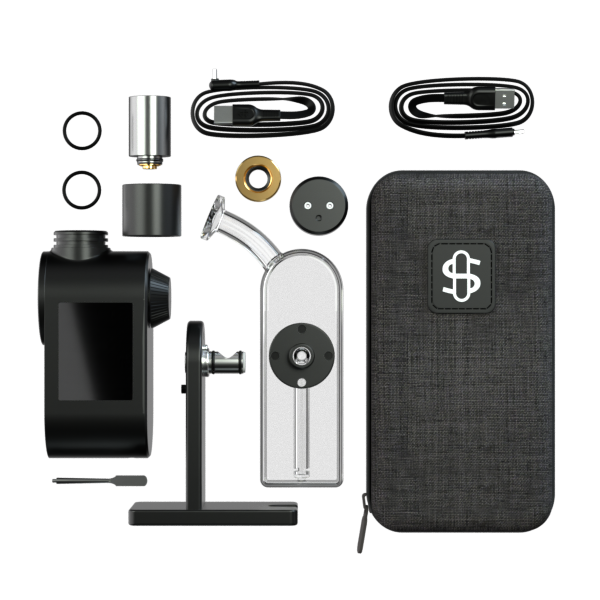 A comprehensive studio knolling shot displaying the Stündenglass Modül + Dok Deluxe Travel Set in Clear Glass alongside all included accessories. The layout features the black travel case, the Modül smart power base, clear glass globe, Dok aluminum stand, dry herb and quartz concentrate tanks, loading tool, magnetic connection ring, carb cap, and USB-C charging cable neatly arranged on a clean background.