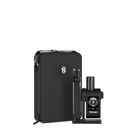 A premium studio product shot displaying the fully assembled Stündenglass Modül + Dok Deluxe Travel Set in Gray Glass standing upright on a clean gray background. Positioned directly next to the elegant, handheld anodized aluminum e-rig is its official hardshell fabric travel case, shown unzipped to highlight its custom-molded protective compartments and rugged drop-resistant build.