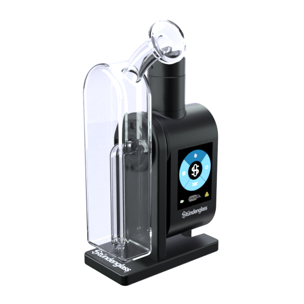 A crisp, front-angle studio product shot of the fully assembled Stündenglass Modül + Dok with Clear Glass. The device is turned slightly to the side to showcase its ergonomic profile, illustrating how the digital Modül battery base sits completely integrated flush within the black anodized Dok station frame beneath the sleek, rounded clear glass filtration globe.