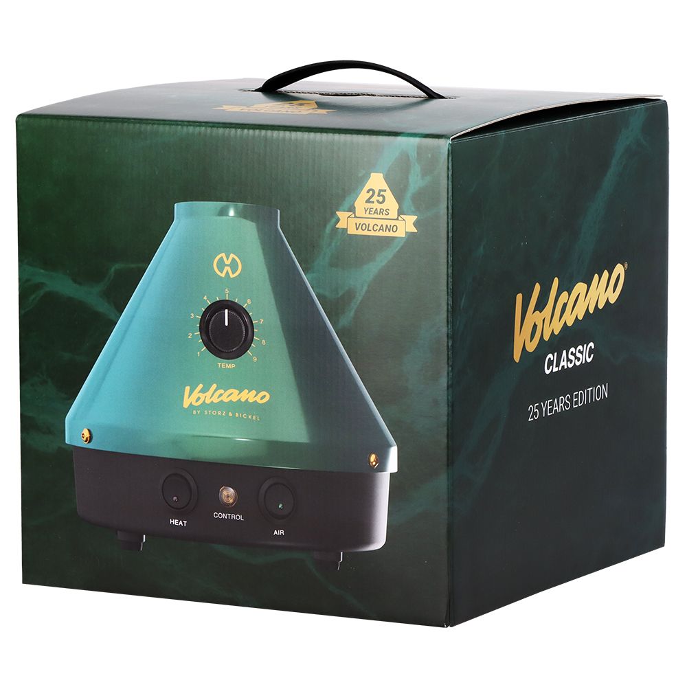 A clean studio product shot of the official Storz & Bickel Volcano Classic 25-Year Limited Edition retail packaging. The box features premium anniversary graphics matching the emerald green and gold colorway of the device inside, displaying the custom collector-tier box art that protects the German-engineered desktop vape.