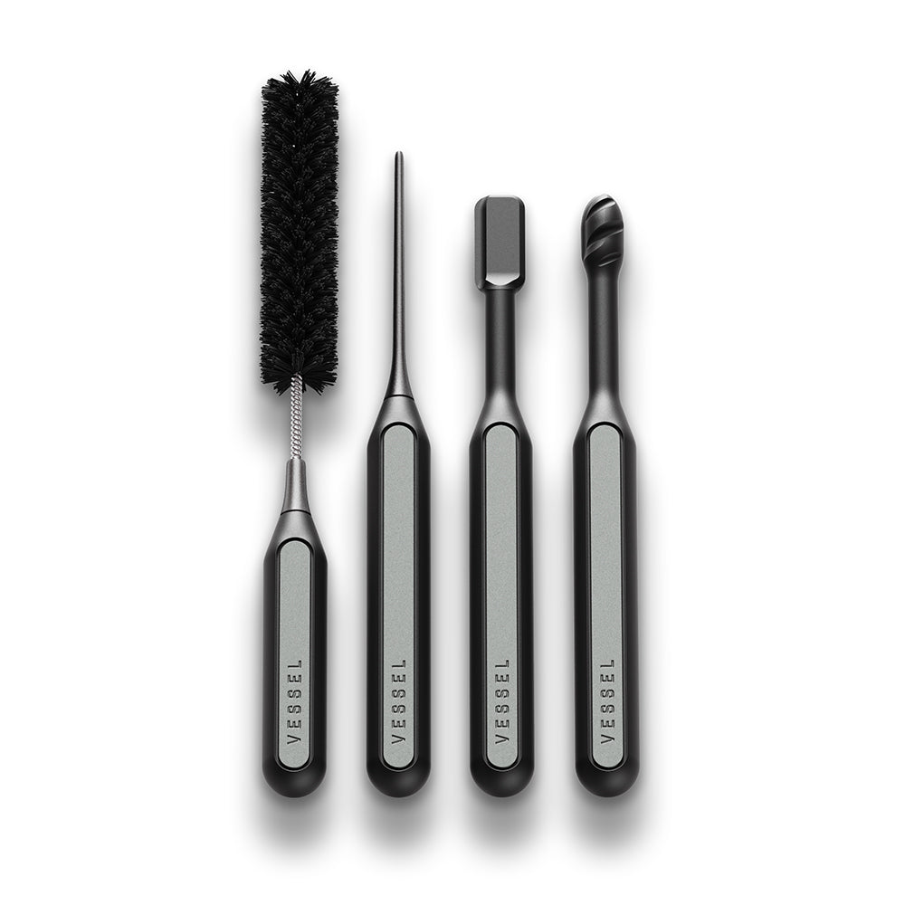 A close-up view focusing exclusively on the four precision-engineered cleaning instruments included in the Vessel Care Kit. The shot displays the Clearing Paddle, Spiral Swab, Sweeping Brush, and Fine Pick side-by-side, highlighting their durable, ergonomic handles and specialized tips designed for restoring and maintaining premium hardware.
