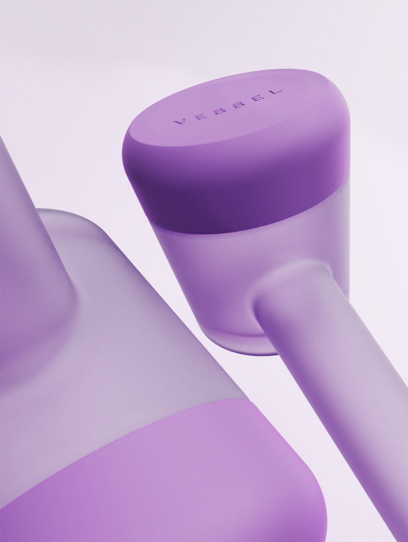 A macro close-up of the Vessel Forge Lilac silicone base. The shot highlights the soft-touch texture and the precise molding where the silicone meets the glass bulb. This protective "boot" is shown in its rich lavender-purple tone, emphasizing the durability and surface-grip features of the design.