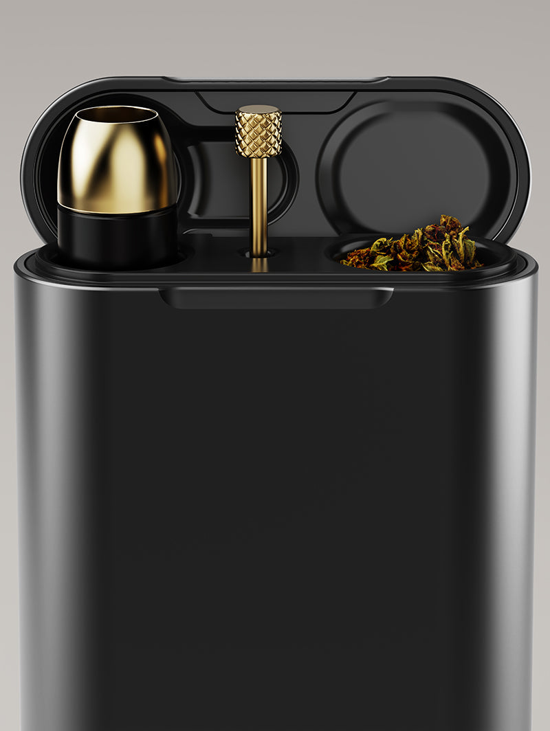 A detailed shot of the Vessel Helix Axis attached to the Helix pipe and resting inside a compatible Vessel Dugout (sold separately). The scene showcases the integrated poker tool and an adjacent compartment containing stored dry herb, demonstrating the Axis as a key component of a high-end, compact travel kit.