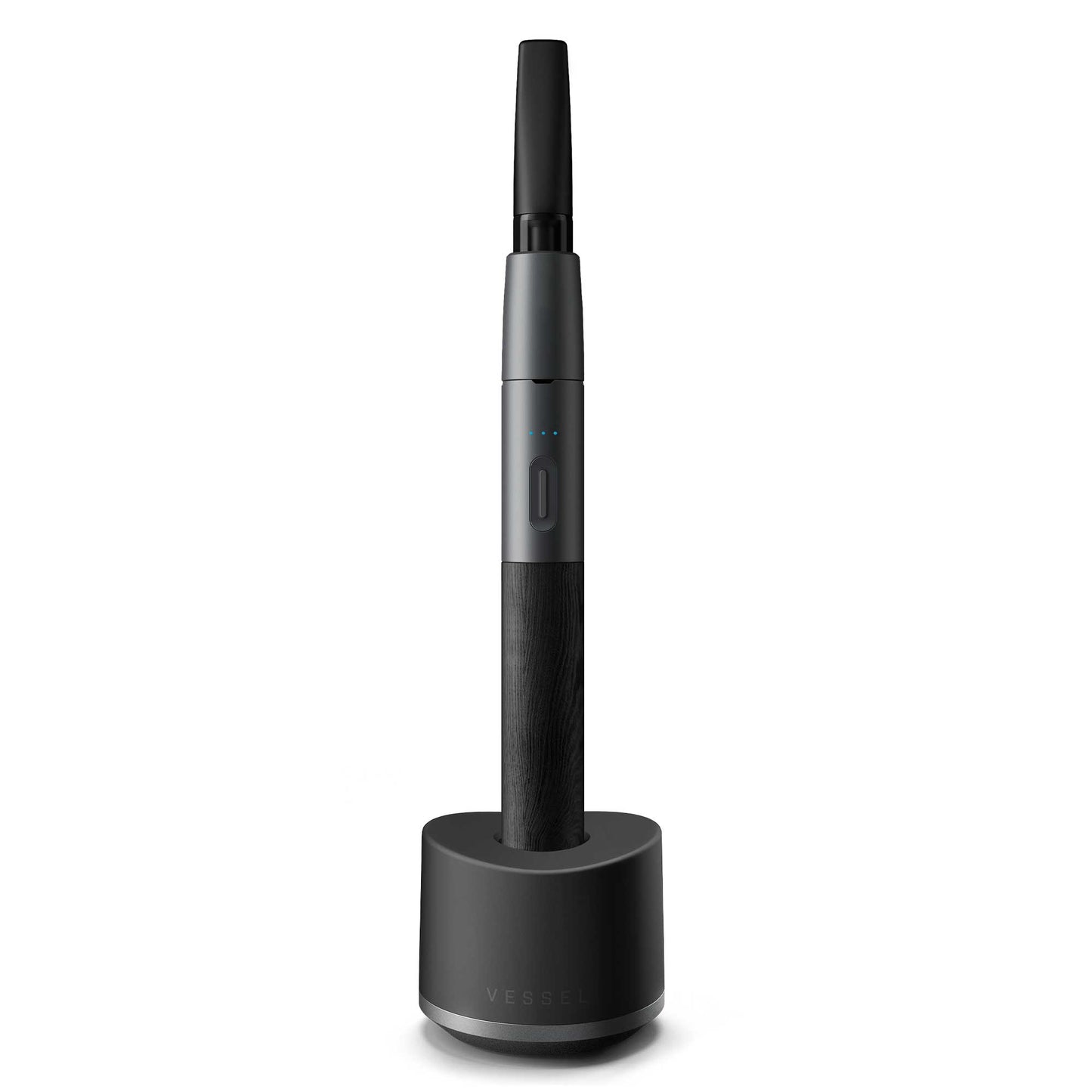 A premium lifestyle studio shot showing the Vessel Wood Series Slate and Blackwood vape pen standing vertically inside the official Vessel Base Charger. The device, equipped with an installed 510 oil cartridge, sits flush within the heavy-duty black desktop charging dock, showcasing how the magnetic contact base seamlessly aligns for a clean, upright desktop charging station.