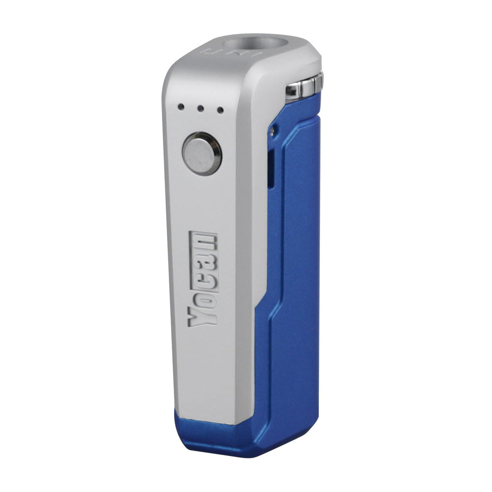 A front-angle studio shot of the Yocan UNI in Blue. The device is finished in a vibrant, royal blue matte. The shot highlights the central silver firing button, the three LED voltage indicators, and the "Yocan" branding debossed on the side of the impact-resistant chassis.